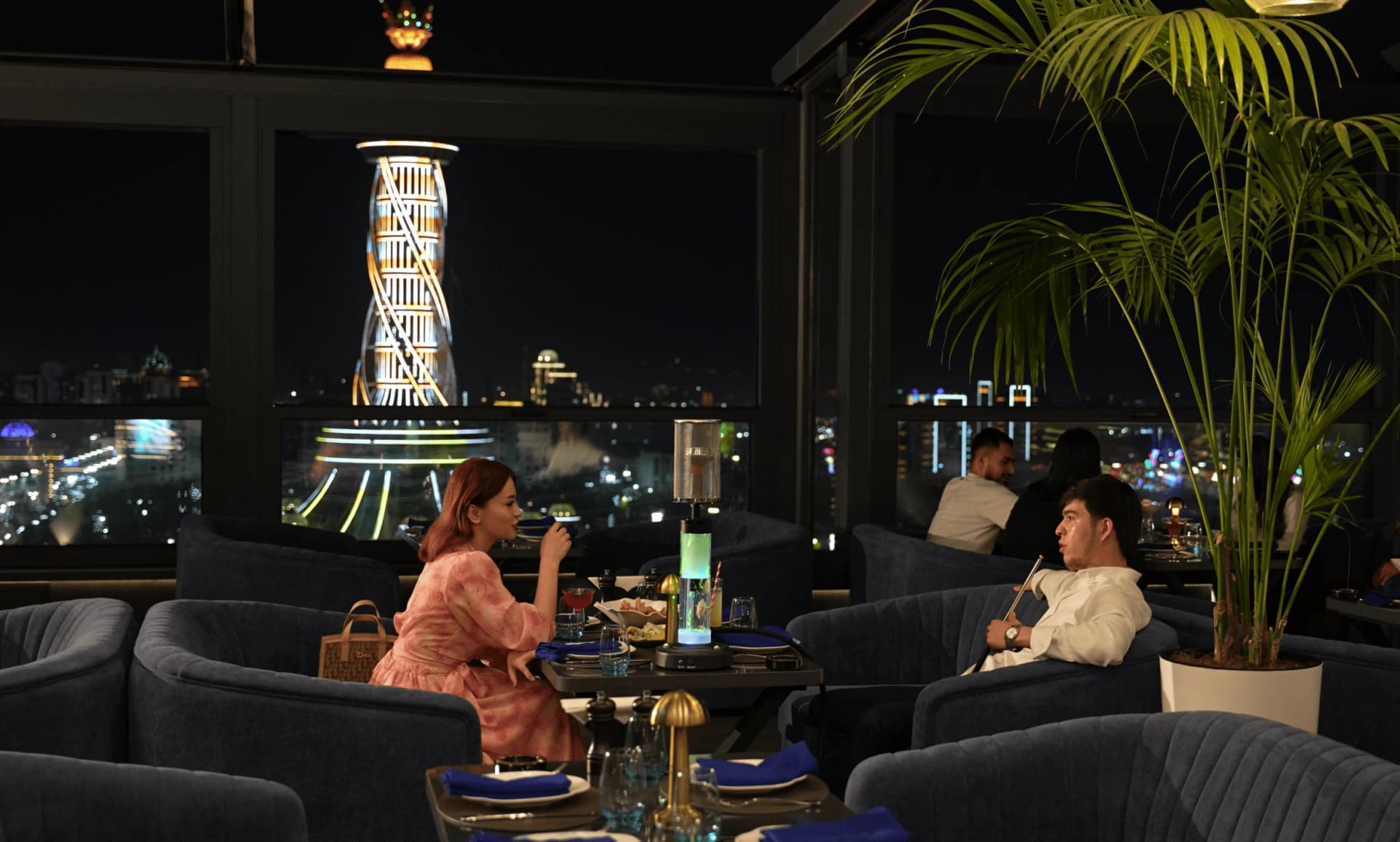 Зал SKY Lounge на закате: стол у панорамного окна и вид на горы